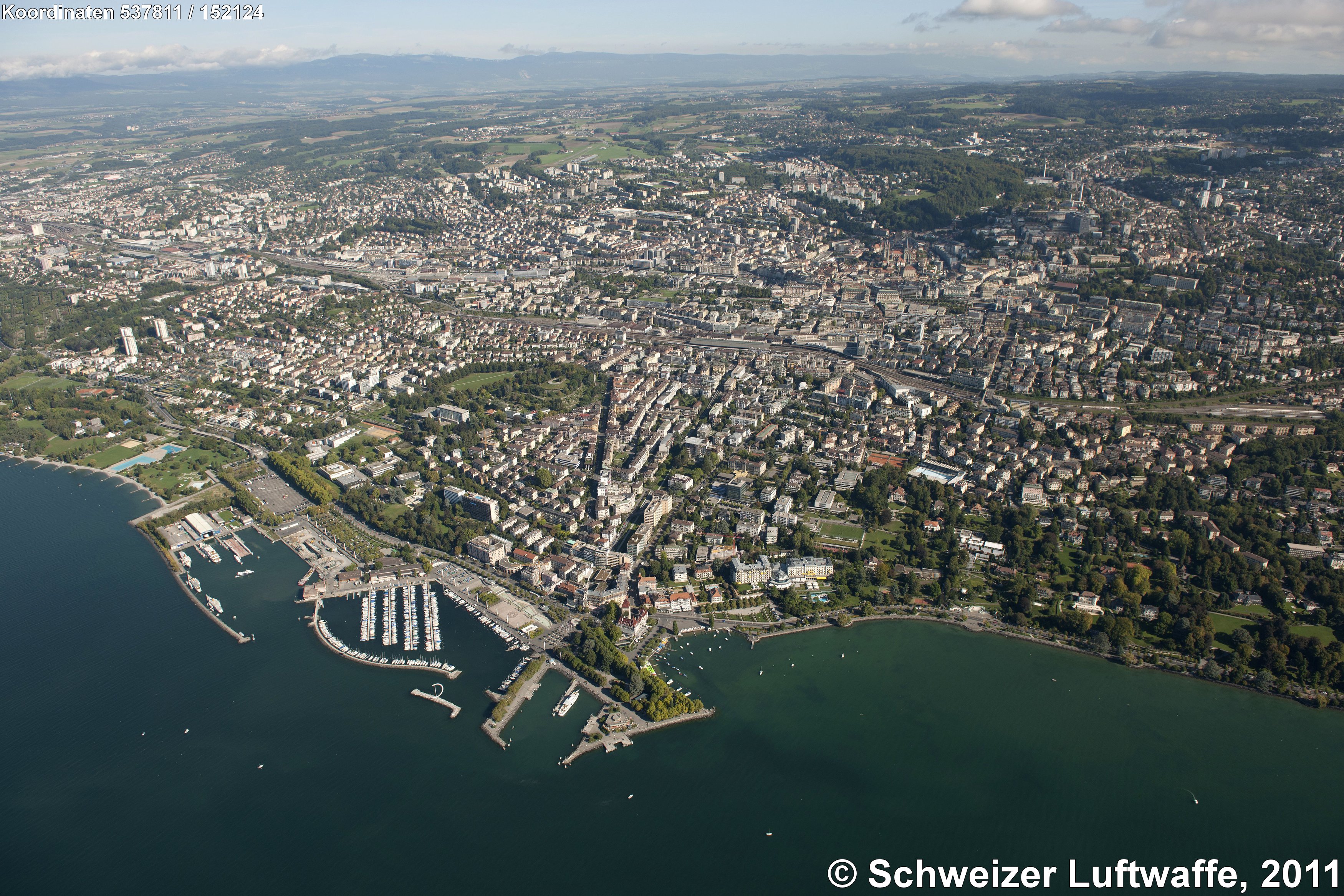 Lausanne, Blickrichtung Nord (Position: 2'537'803.73, 1'152'224.36). - Viertgrösste Stadt der Schweiz nach Basel, Genf und Zürich; Hauptstadt des Kantons Waadt. - Im Bildvordergrund: Freizeithafen und Seepromenade von Ouchy mit dem neugotischen Schloss und diversen markanten Hotelbauten des 19. Jahrhunderts. Rechts am Ufer des Lac Léman: Grünanlagen des Parc Olympique.