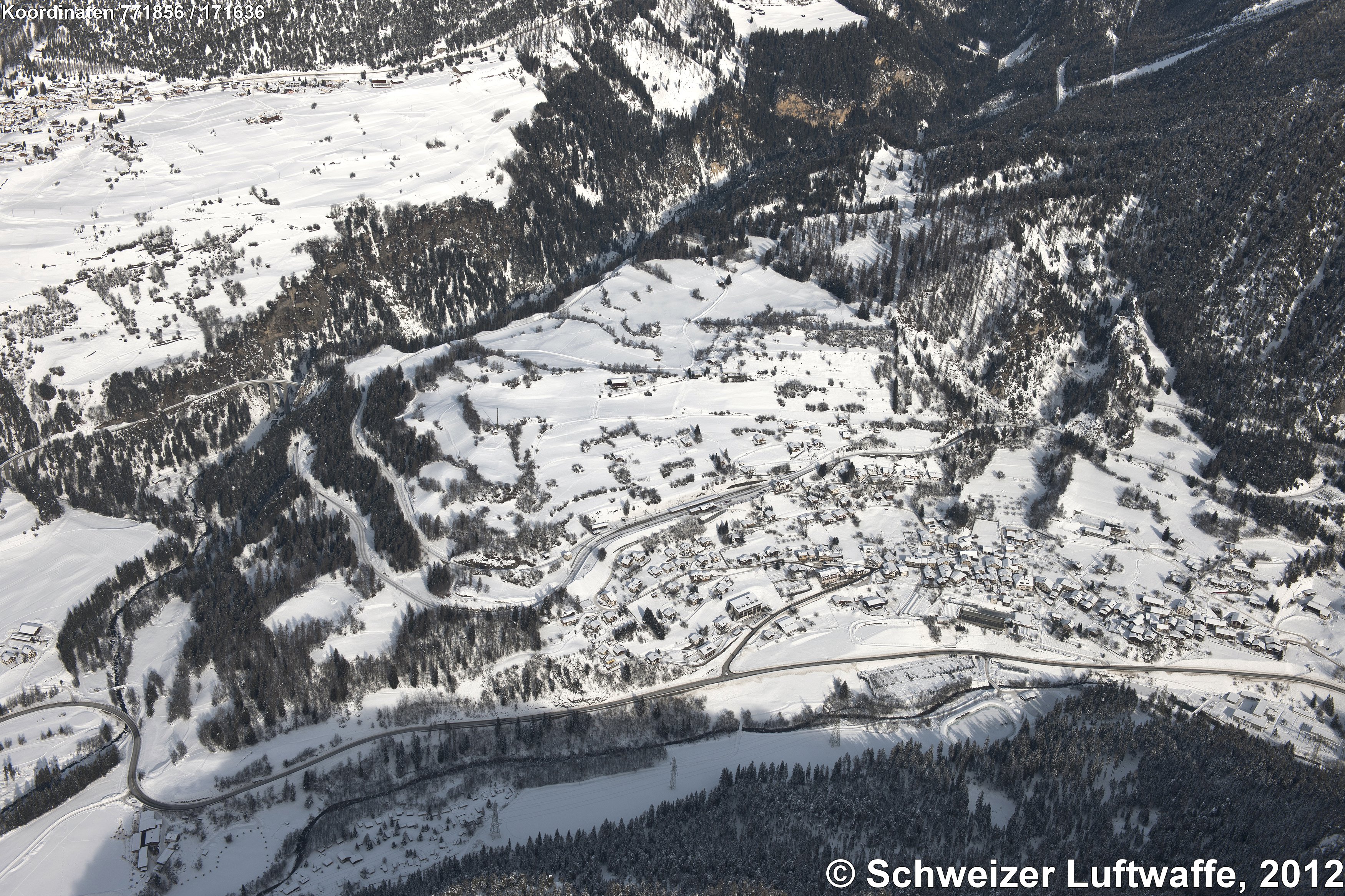 Filisur (Position: 2'771'849.41, 1'171'706.93), Blick nach Norden. - Fluss im Vordergund: Albula / Alvra. - Seit 2018 heisst die Gemeinde Bergün Filisur. - Broncezeitliche Funde sind älteste Zeugnisse der Besiedelung. Erwähnt ist der Name 'villa Fallisour' erstmals 1262. Die Burgruine Greifenstein, NE von Filisur, war Sitz des hochadligen Bündner Geschlechtes 'Greifenstein'. - Im Hochmittelalter besiedelten die Rätoromanen das Albulatal; die Maiensässen (Jenisberg, 4 km NE Filisur; Position 2'775'104.41, 1'174'395.98) besiedelten im 15.. Jhd deutschsprachige Walser.